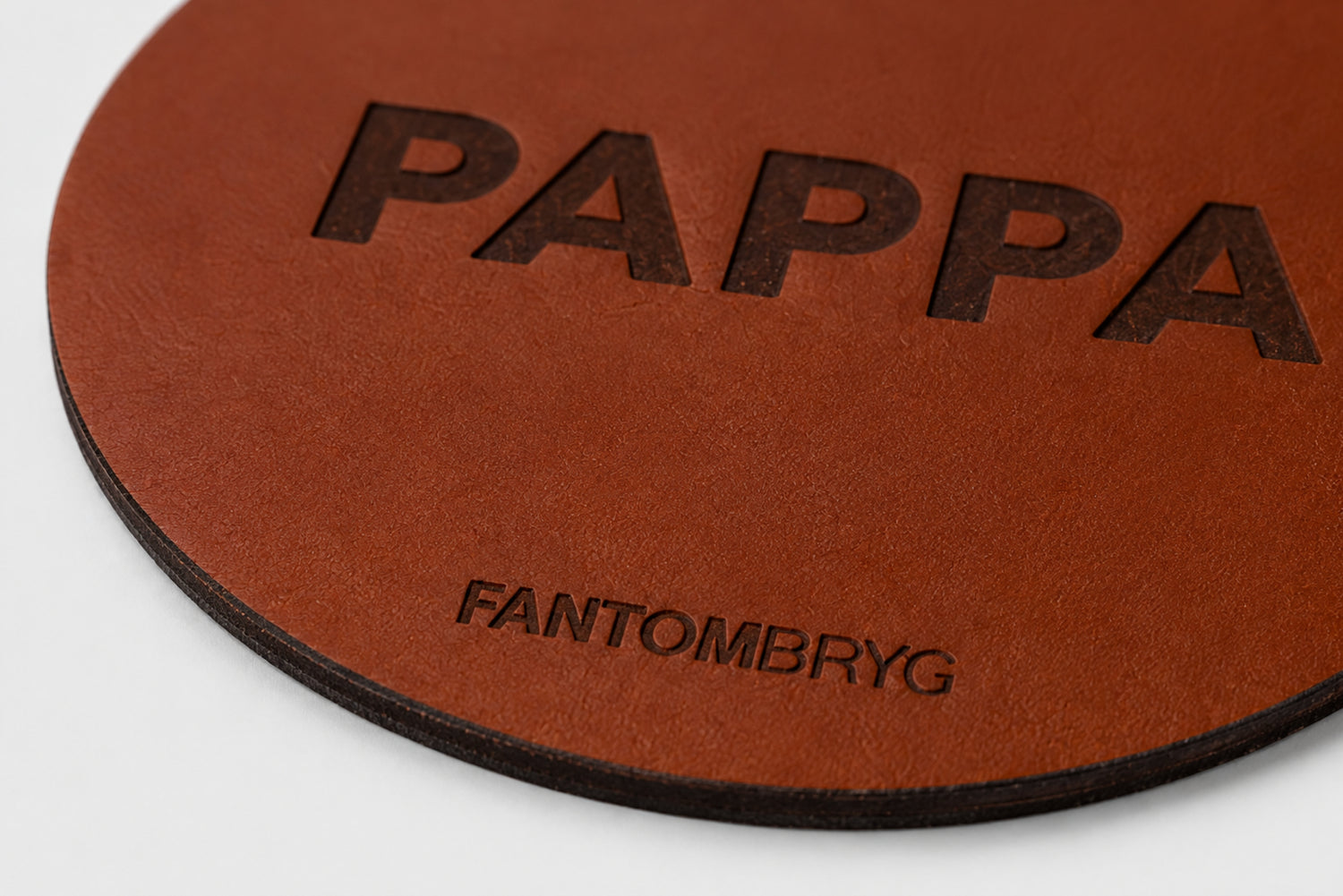 Detalj av ölunderlägg i äkta läder med präglad PAPPA-text och Fantombryg-logo