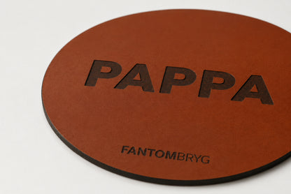Närbild på brunt ölunderlägg i äkta läder med PAPPA-prägling